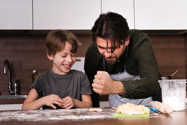 Low angle father and son rolling dough