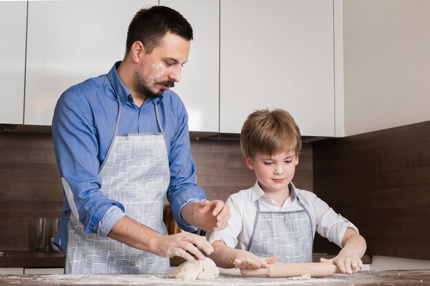 Free photo low angle father and son rolling dough