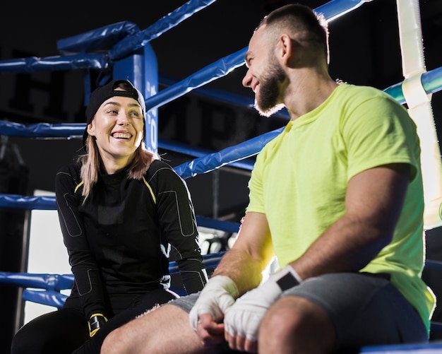 Angolo basso del pugile femminile e trainer maschio che hanno una conversazione accanto al ring