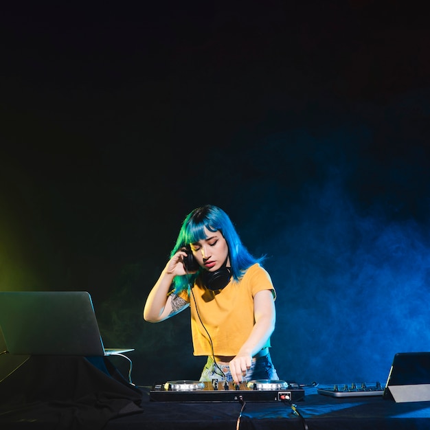 Low angle female dj concentrated at panel