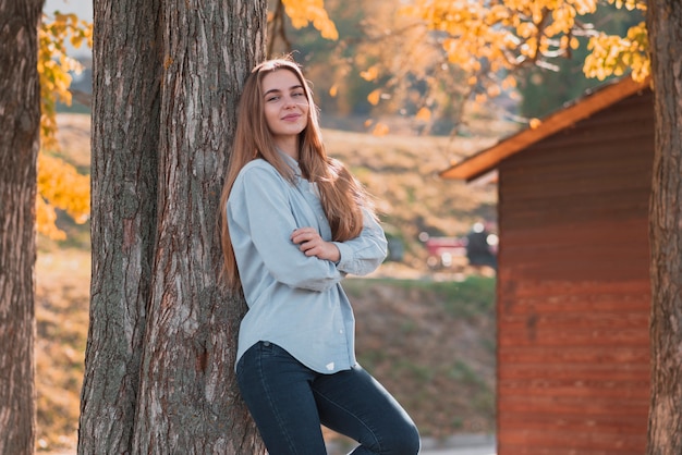Low angle female in par standing next to tree