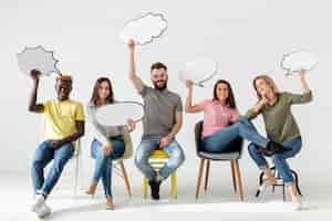 Free photo low angle friends on chairs with chat bubbles