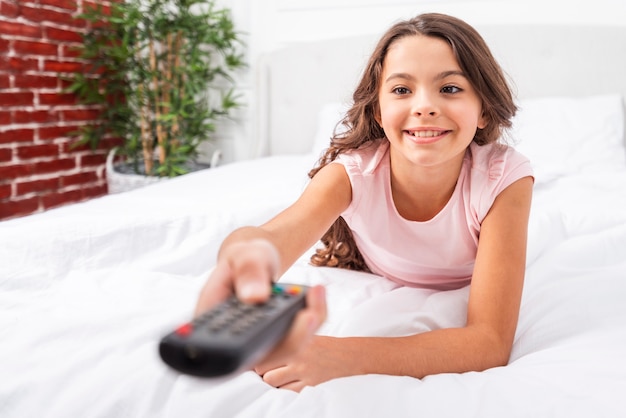 Low angle girl on bed holding remote control