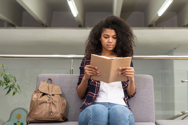 Free photo low angle girl on couch reading