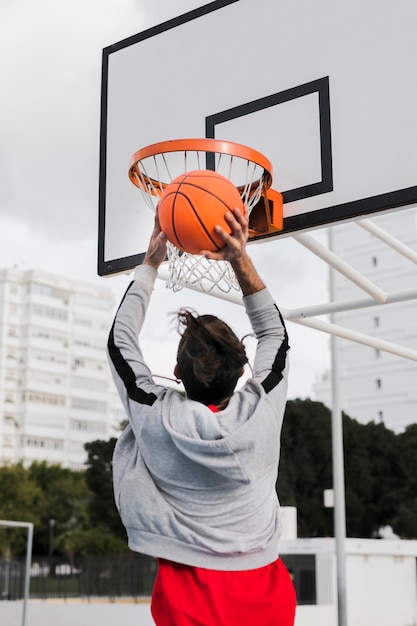 Low angle of girl  throwing in basketball hoop