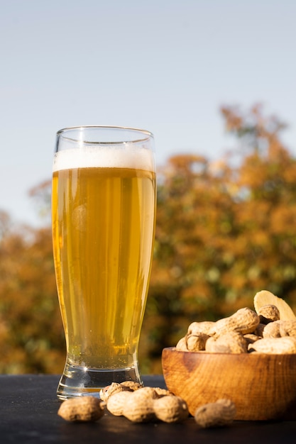 Low angle glass with beer beside peanuts