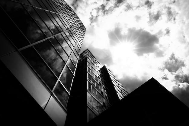 Low angle grayscale shot of business buildings with a cloudy sky in the background