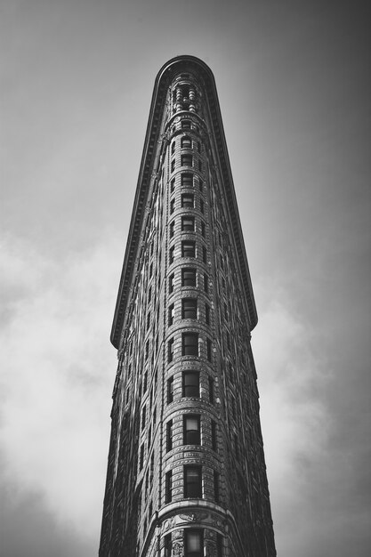 Низкий угол съемки в оттенках серого любопытного Flatiron Building в Манхэттене, Нью-Йорк, США