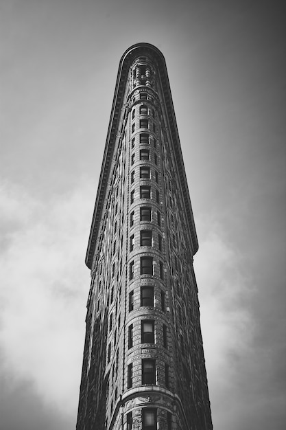 Низкий угол съемки в оттенках серого любопытного Flatiron Building в Манхэттене, Нью-Йорк, США