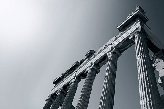 Low angle greyscale shot of an ancient Roman temple under the bright sun