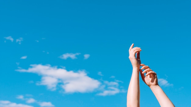 Free Photo low angle of hands raised up with sky and clouds
