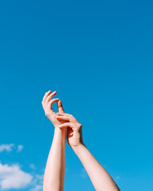 Foto gratuita angolo basso delle mani sollevate con lo spazio della copia e del cielo