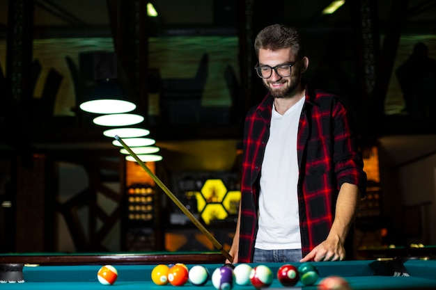 Free photo low angle happy guy looking at pool table