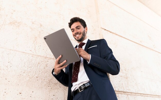 Low angle happy man working on tablet