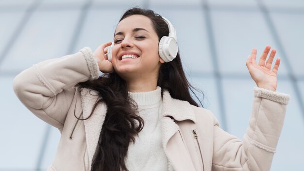 low angle of happy woman listening to music on headphones