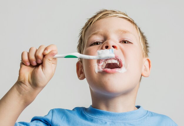 Low angle kid brushing his teeth