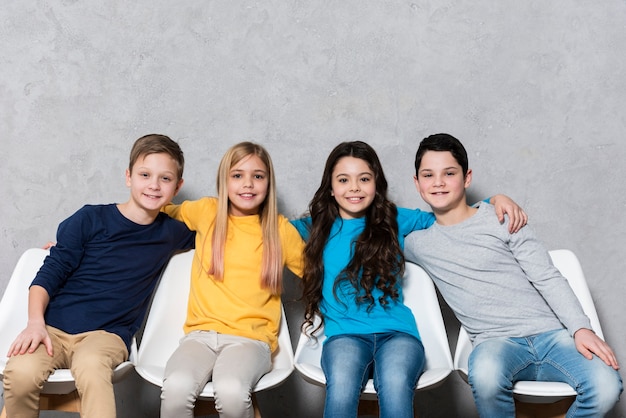 Low angle kids sitting on chairs