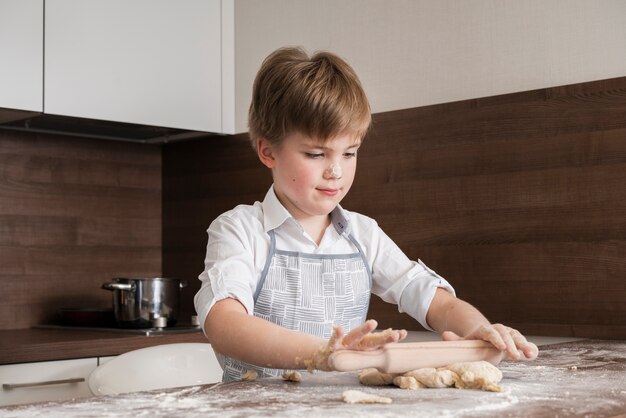 Low angle little boy at home rolling dough