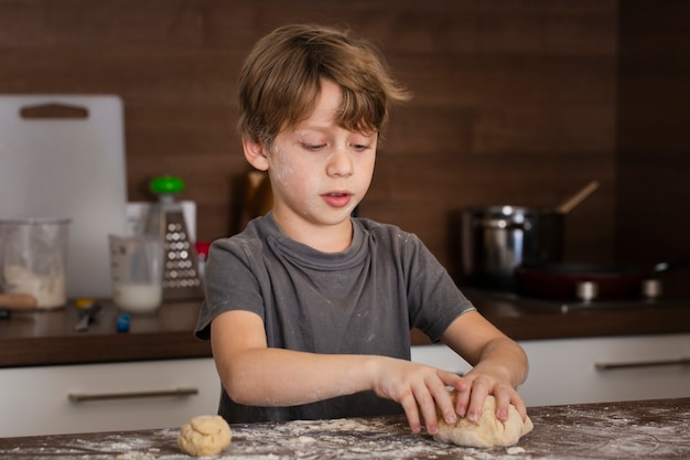 Free photo low angle little boy making dough