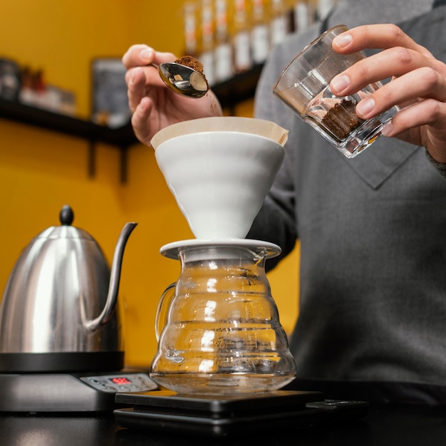 Free photo low angle of male barista putting coffee in filter