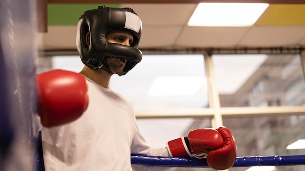 Low angle of male boxer with helmet and gloves