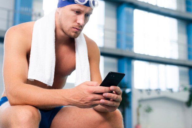 Low angle male swimmer checking mobile