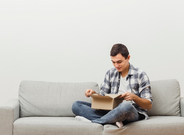 Low angle man on couch opening box