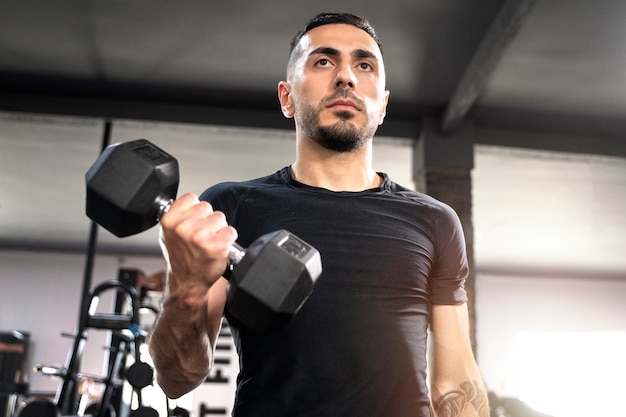 Low angle man holding dumbbell