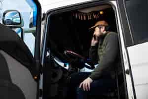 Foto gratuita uomo di angolo basso che parla al telefono in camion