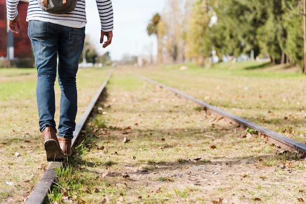 Low angle man walking on train tracks