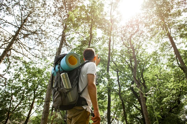 Low angle man with backpack in forest