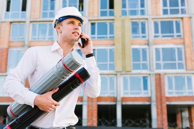 Uomo di angolo basso con il casco che parla sul telefono