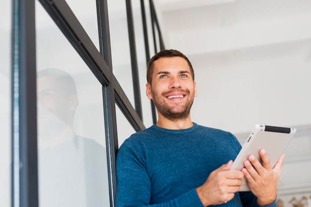 Low angle man with tablet at home