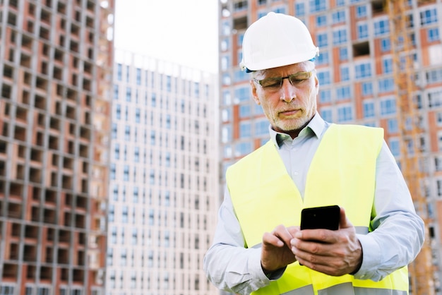 Low angle old man looking at smartphone