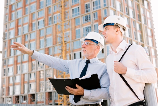 Free photo low angle old man with helmet pointing at something