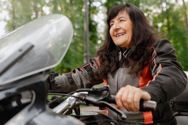 Foto gratuita vecchia donna ad angolo basso con una motocicletta fantastica