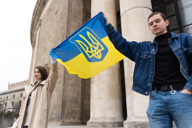 Люди под низким углом держат украинский флаг