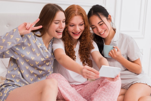 Low angle playful girlfriends taking selfie