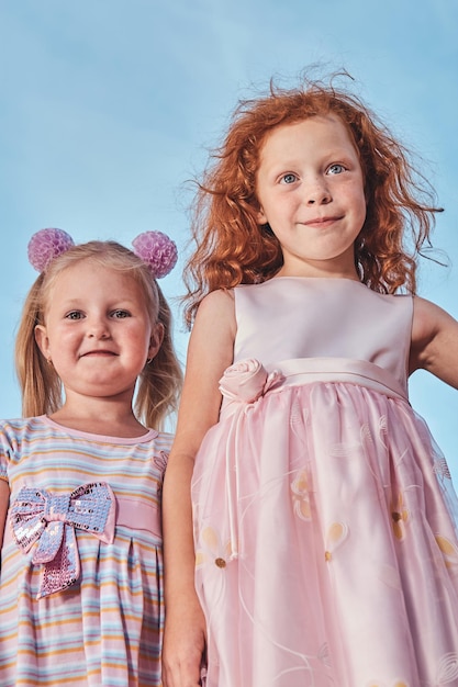 Низкоугольный портрет счастливых милых маленьких друзей на фоне неба.