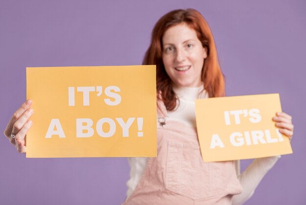 赤ちゃんの性別と紙を保持している低角度の妊娠中の女性