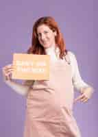 Free photo low angle pregnant woman pointing at paper with baby on the way message