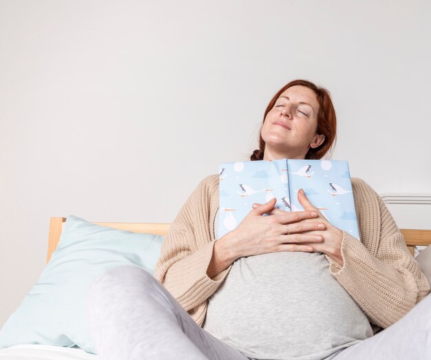 Low angle pregnant woman reading baby books