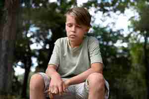 Free photo low angle sad boy sitting outdoors