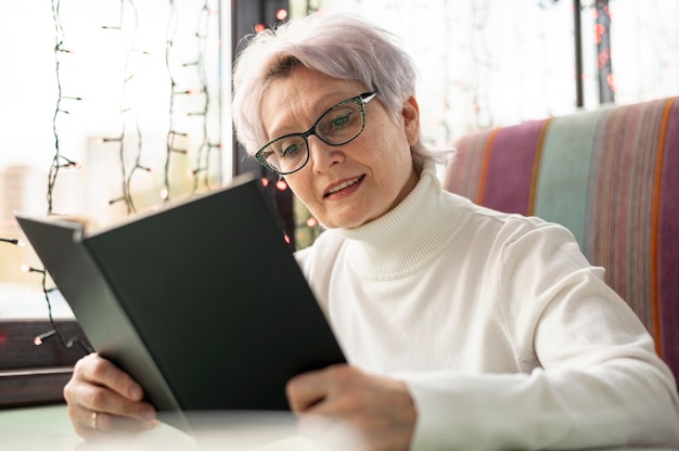 Free photo low angle senior woman reading