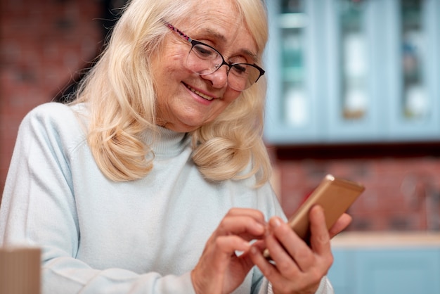 Foto gratuita donna senior di angolo basso che usando cellulare