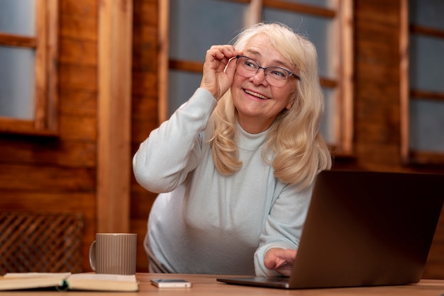 Free photo low angle senior woman working on laptop