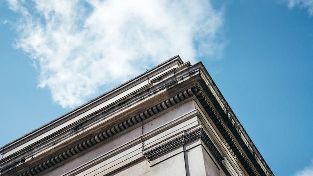 Foto gratuita colpo di angolo basso di una costruzione architettonica sotto un chiaro cielo blu con le nuvole bianche