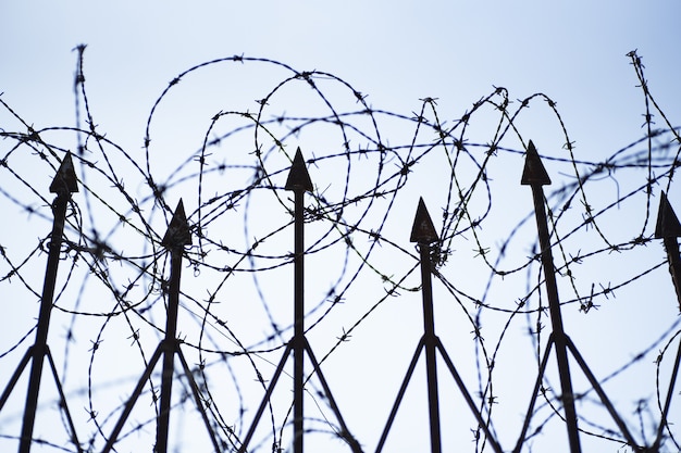 Low angle shot of a barbed-wire fence under the clear blue sky