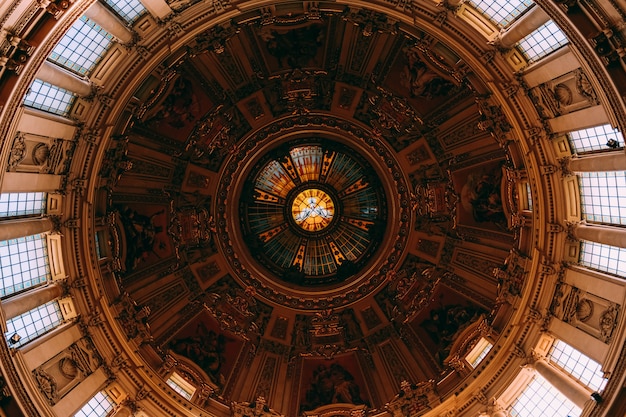 Low angle shot of the beautiful painting and windows on a ceiling in an old building