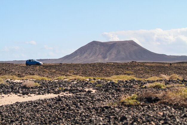 フェルテベントゥラ島、カナリア諸島の丘の横に駐車した青い車のローアングルショット